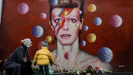 Flowers and other mementos piled up beneath a mural of David Bowie painted by Australian street artist James Cochran, aka Jimmy C, in Brixton, South London.